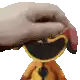 a hand is holding a stuffed animal with a big smile on its face .