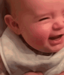 a close up of a baby crying with his eyes closed .