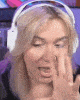 a woman wearing headphones is making a funny face and covering her nose .