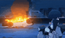 a man in a mask stands in front of a burning car