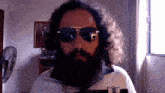 a man with a beard wearing sunglasses and a shirt with a patch on it