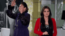 a woman in a purple dress stands next to another woman in a red jacket