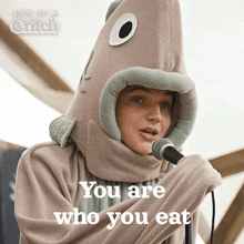 a person in a fish costume is singing into a microphone with the words you are who you eat below them