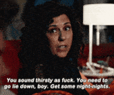 a woman with curly hair is sitting on a couch talking to another woman .