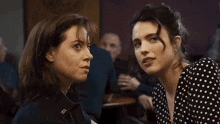 two women are sitting next to each other and one of them has a pin on her jacket that says eee