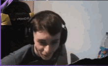 a young man wearing headphones and a microphone is sitting in a chair .