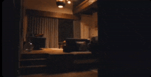 a dark living room with a couch and chairs and a window