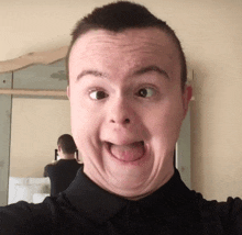 a man in a black shirt is making a funny face in front of a mirror
