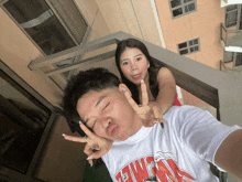 a man wearing a shirt that says chicago is giving a peace sign next to a woman