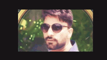 a man with a beard is wearing sunglasses and looking at the camera
