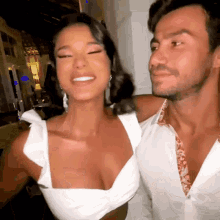 a man and a woman are posing for a picture and the woman is wearing a white top