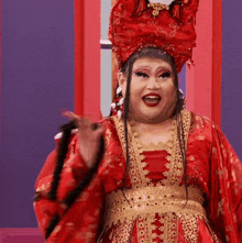 a woman in a red and gold costume is holding a black whip