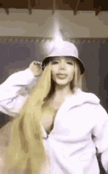 a woman with long blonde hair is wearing a bucket hat and a white shirt .