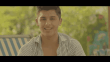 a young man wearing a striped shirt is smiling for the camera