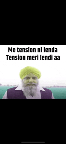 a man with a beard and a turban on his head is standing in front of a body of water .