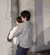 a man in a plaid shirt is carrying another man on his shoulders .