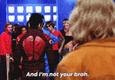 a man in a red jacket stands in front of a crowd and says and i 'm not your brah