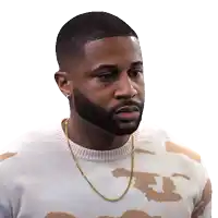 a man with a beard is wearing a sweater with the letter t on the front