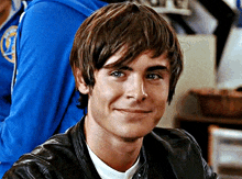 a young man wearing a leather jacket and a white shirt smiles for the camera