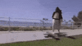 a woman is standing on a bench in a park with a bag .