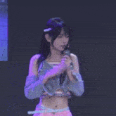 a young woman is standing on a stage wearing a crop top and gloves .
