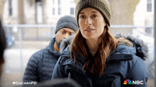 a woman wearing a beanie and a jacket with nbc written on the bottom