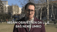 a man wearing glasses says nisam obavezten da li je bas neko umro in front of a park