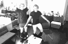 two men are standing next to each other in a living room .