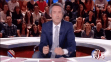 a man in a suit and tie stands in front of a crowd of people on a tmc television show