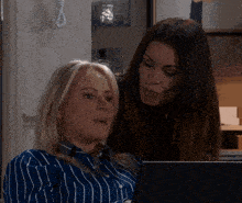 two women are looking at a laptop screen together