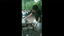 a man in a black shirt is kneeling down in front of a wood burning stove .