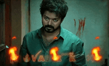 a man with a beard and a green shirt is standing in front of a wall with blood on it .