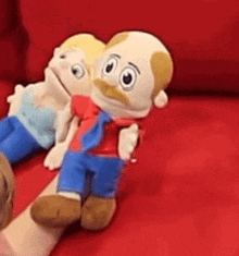 a couple of stuffed animals sitting on a red couch