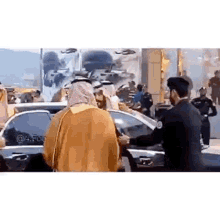 a man in a turban is talking to a police officer in front of a crowd of people .