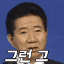 a man in a suit and tie is making a funny face with korean writing on his face .