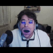 a man wearing headphones and glasses is making a funny face in front of a microphone