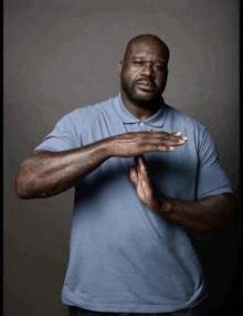 a man wearing a blue shirt is making a stop sign