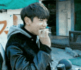 a young man is smoking a cigarette in front of a building with the letter u on it