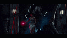 a woman holding a red light stands in front of a large dinosaur