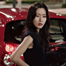 a woman is standing in front of a red car .