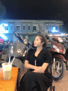 a woman sits at a table in front of a row of scooters