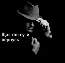 a black and white photo of a man wearing a fedora
