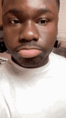 a close up of a man 's face with a white shirt on .
