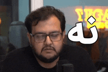 a man with glasses and a beard is sitting in front of a sign that says ' tkg ' on it