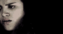 a close up of a woman 's face with a black background and a serious look on her face .