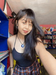a girl wearing a plaid skirt and a black tank top is taking a selfie