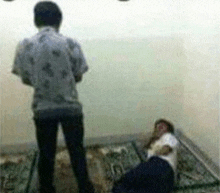 a man standing next to a man laying on the floor .