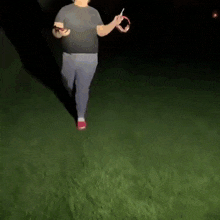 a man in a black shirt and gray pants is standing in the grass at night