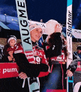 a woman holding a pair of skis that say augme on it