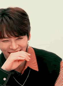 a young man is laughing with his hand on his mouth .